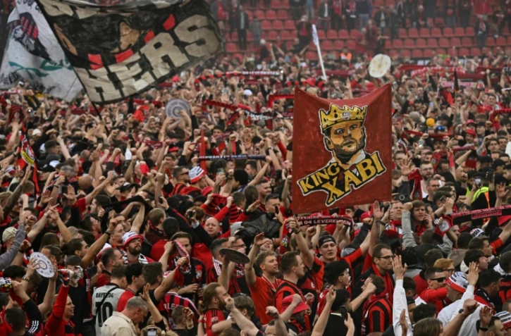 Les supporters du club de football du Bayer Leverkusen célèbrent la victoire de leur club en championnat d'Allemagne après sa victoire 5-0 contre le Werder Brême au stade de Leverkusen le 14 avril 2024.