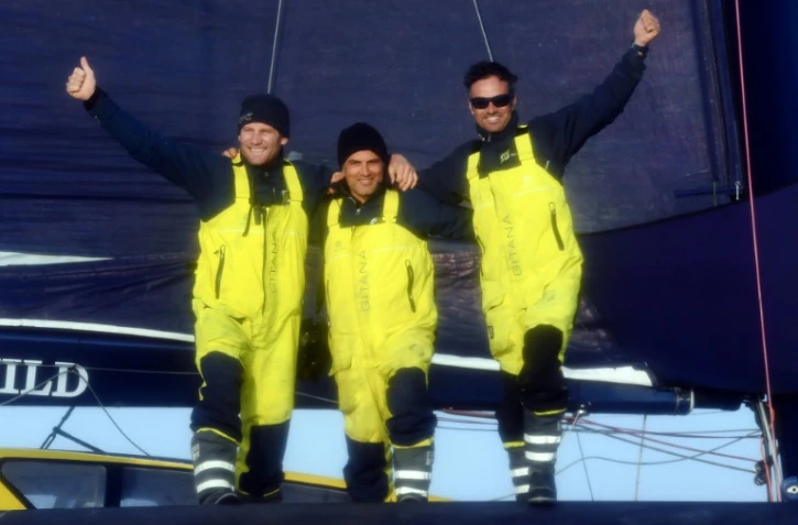 Franck Cammas (g) et Charles Caudrelier (d) avec leur "Media Man" Yann Riou à bord de leur Maxi Edmond de Rothschild à l'arrivée de la Brest Altantiques, le 4 décembre 2019 à Brest  