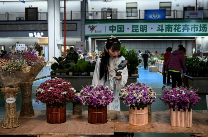 Une influenceuse propose en direct via son smartphone des bouquets aux internautes depuis le marché aux fleurs de Dounan à Kunming, en Chine, le 22 octobre 2021