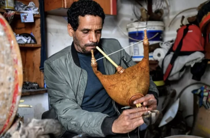 L'artisan tunisien Khaled ben Khemis souffle dans un mezoued dans un atelier près de Tunis, le 24 mai 2023 ( AFP / FETHI BELAID )