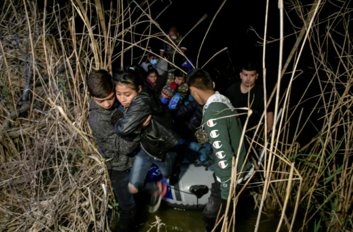 Un groupe de migrants venus du Honduras et du Guatemala débarque du bateau d'un passeur mexicain après avoir traversé le Rio Grance à Roma, au Texas, le 28 mars 2021.