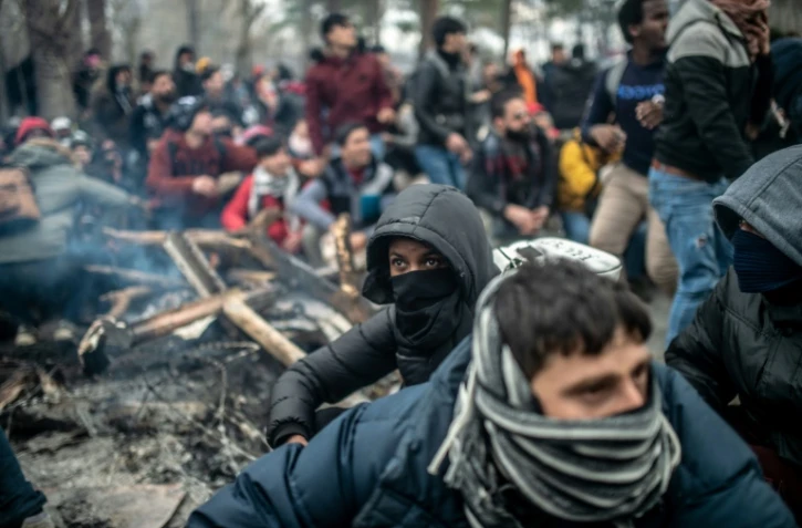 Des migrants attendent dans la zone-tampon entre la Turquie et la Grèce après des heurts avec les forces de l'ordre grecques tentant de les empêcher de franchir la frontière à Kastanies/Pazarkule, le 29 février 2020