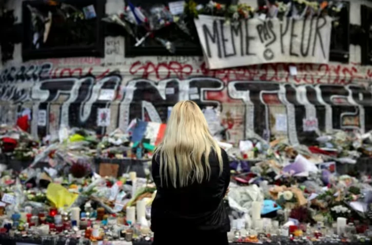 Une femme se recueille devant un mémorial improvisé composé de fleurs, de bougies et de messages, place de la République à Paris, le 17 novembre 2015, en hommage aux victimes des attentats du 13 novembre 2015 ( AFP / Kenzo TRIBOUILLARD )