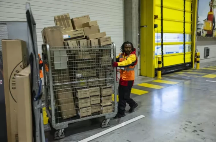 Un employé pousse un conteneur de colis dans un entrepôt à Lesquin, près de Lille, le 12 novembre 2025 ( AFP / Sameer Al-DOUMY )