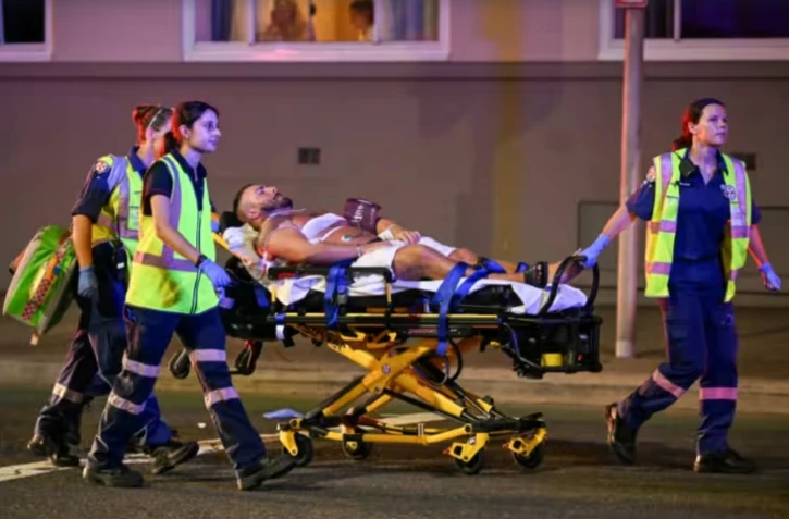 Un homme acheminé sur un civière après une attaque par balles qui a fait onze morts sur la plage de Bondi à Sydney, le 14 décembre 2025 ( AFP / Saeed KHAN )
