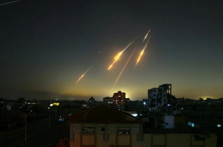 Une photo prise depuis la bande de Gaza montre des traînées de missiles dans le ciel tard le 13 juin 2025, après que l'Iran a tiré des missiles sur Israël 
