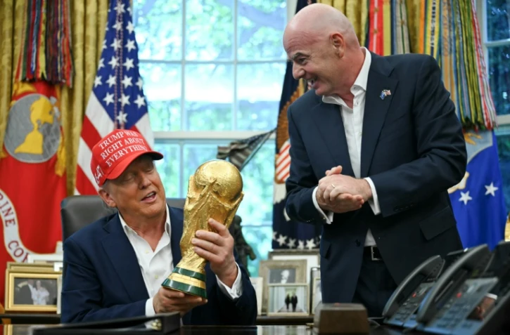Le président Donald Trump et celui de la Fifa Gianni Infantino, avec le trophée de la Coupe du monde dans le bureau ovale, le 22 août 2025 à Washington, DC