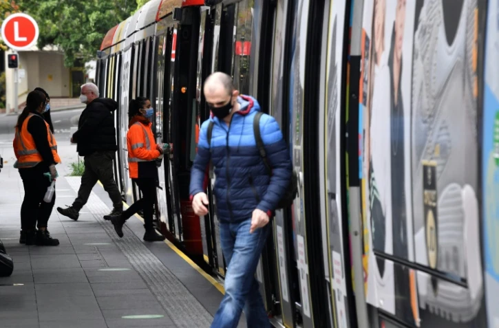 Des passagers portant le masque descendent d'un métro le 23 juin 2021 à Sydney où de nouvelles restrictions sont en vigueur