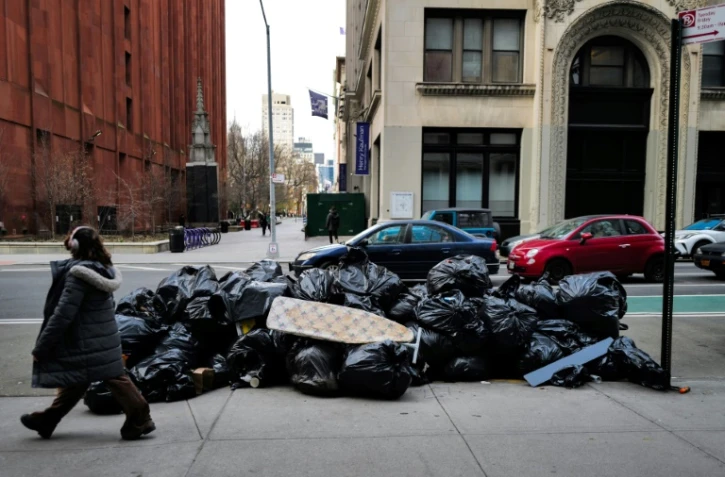Une femme devant un tas de poubelles à Manhattan, New York le 19 mars 2024
