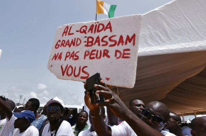 Des Ivoriens portent une pancarte "Al-Qaïda, Grand-Bassam n'a pas peur de toi", lors d'un hommage aux victimes de l'attaque jihadistes du 13 mars 2016 qui a fait 19 morts, le 20 mars 2016 à Grand-Bassam en Côte d'Ivoire