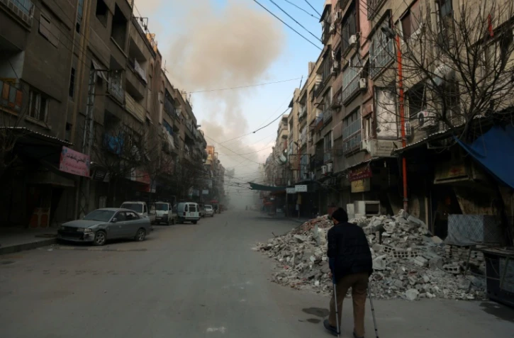 Un homme marche avec des béquilles dans une rue de la ville de Douma, dans la Ghouta orientale, après un bombardement du régime, le 23 février 2018