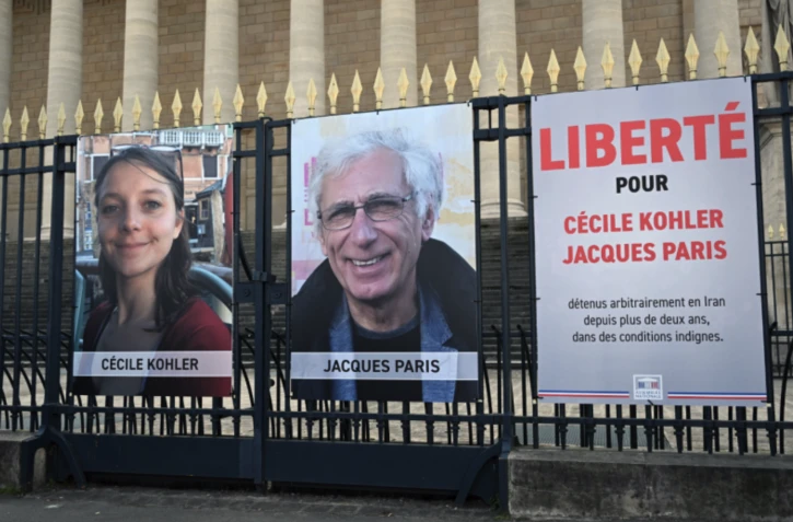  Cette photographie montre les portraits de Cécile Kohler (G), actuellement emprisonnée en Iran, et de son compagnon Jacques Paris (C), devant le Palais Bourbon, l'Assemblée nationale française, après leur rencontre avec le président de l'Assemblée nationale française, à Paris, le 25 mars 2025. Photo AFP / BERTRAND GUAY 