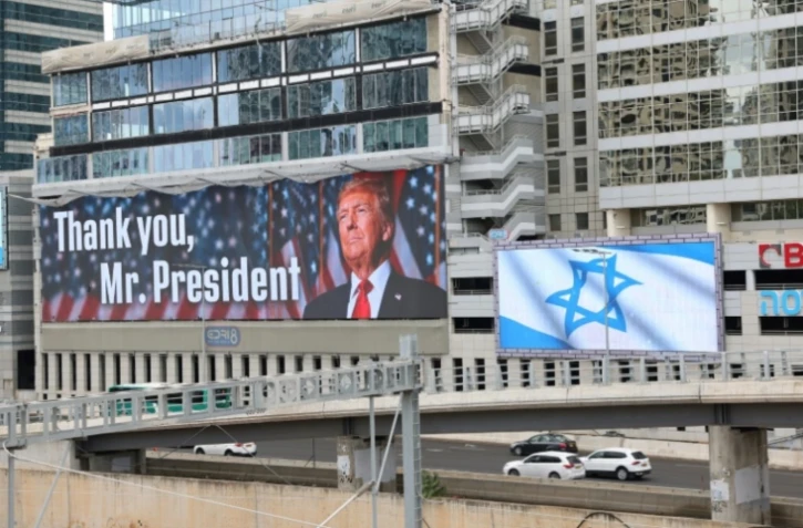 Un panneau d'affichage à Tel-Aviv montre une photo du président américain Donald Trump avec l'inscription "Merci, président Trump" et un autre arbore le drapeau israélien, après l'accord sur Gaza, le 9 octobre 2025 ( AFP / Jack GUEZ )