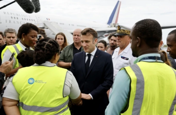 Emmanuel Macron s'entretient avec des membres du personnel de l'aéroport de Dzaoudzi, à Mayotte, le 19 décembre 2024 ( POOL / Ludovic MARIN )