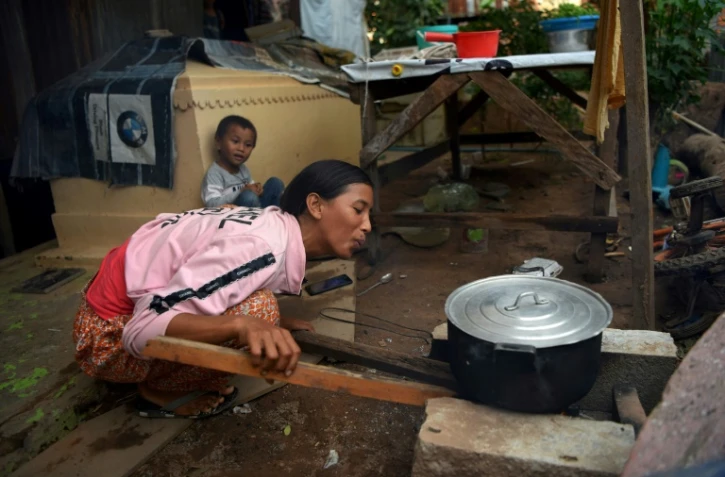 Une femme prépare le dîner près d'une tombe, le 21 mai 2019 dans un vieux cimetière de Phnom Penh, au Cambodge