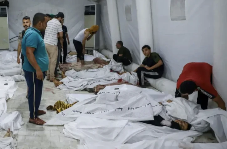 Des gens s'occupent de corps de personnes tuées dans une frappe israélienne sur l'hôpital Ahli Arab, dans la ville de Gaza, transportés dans l'hôpital d'Al Chifa le 17 octobre 2023 ( AFP / Dawood NEMER )