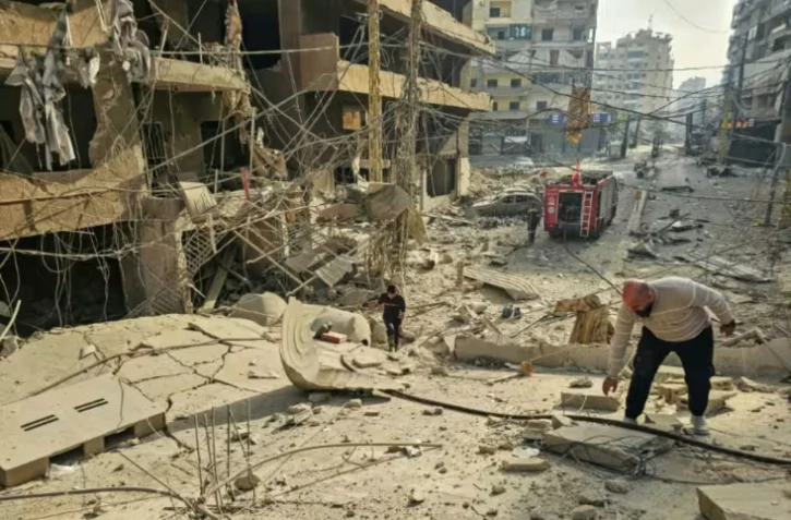 Des pompiers près d'un immeuble détruit sur le site de frappes aériennes israéliennes nocturnes dans la banlieue sud de Beyrouth, le 12 mars 2026 au Liban ( AFP / - )