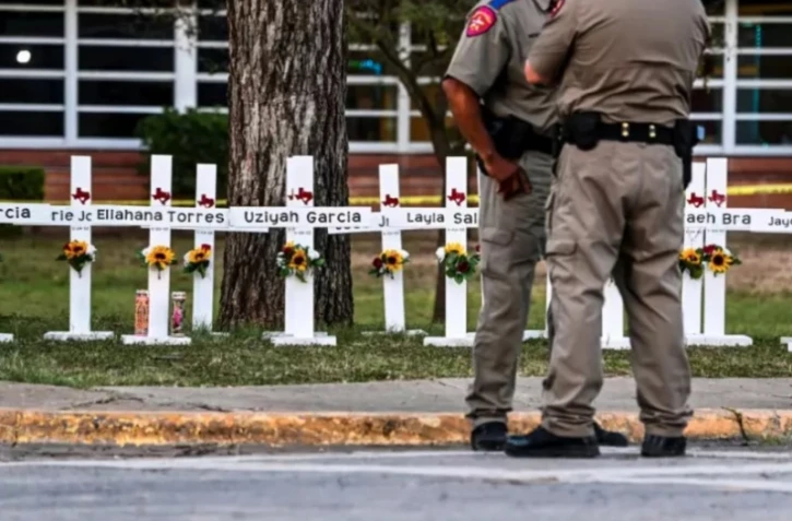 Des policiers se tiennent le 26 mai 2022 devant un mémorial de fortune pour les victimes de la fusillade dans l'école primaire Robb d'Uvalde au Texas ( AFP / CHANDAN KHANNA )