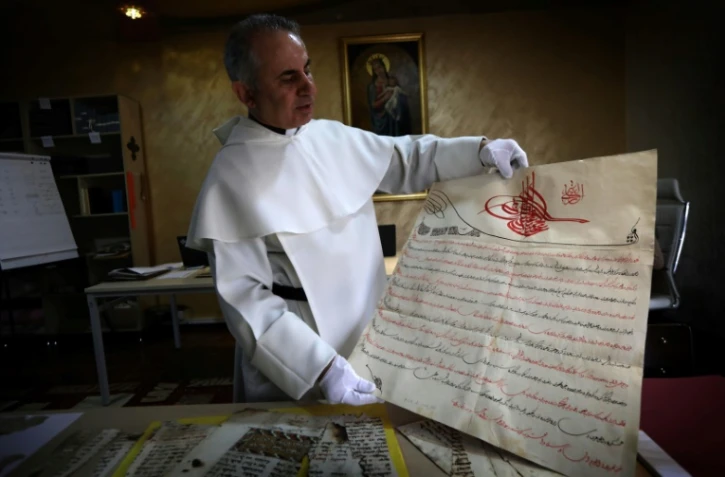 Le père Najeeb Michaeel
montre un manuscrit au Centre de numérisation des manuscrits orientaux (CNMO) à Erbil, dans le nord de l'Irak, le 1er mars 2018