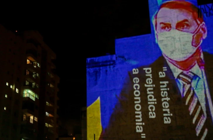 Une image du président brésilien Jair Bolsonaro, accompagné de la phrase "l'hystérie fait du mal à l'économie", est projetée sur le mur d'un immeuble à Sao Paulo le 21 mars 2020, dans le cadre de plusieurs actions critiquant la position du chef de l'Etat