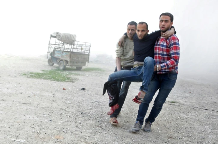 Des Syriens transportent un homme blessé par des bombardements du régime syrien sur la localité rebelle de Aïn tarma dans la Ghouta orientale près de Damas, le 21 mars 2018