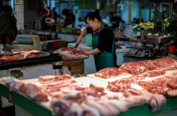 Une vendeuse coupe du porc sur un marché de Hangzhou, dans la province du Zhejiang, dans l'est de la Chine, le 10 avril 2025