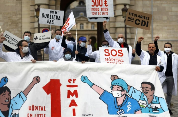 Des personnels soignants et membres du syndicat français CGT manifestent le 30 avril 2020 devant l'hôpital public parisien de la La Pitié Salpêtrière à la veille du 1er mai.