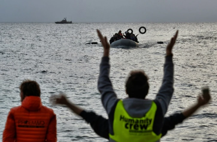Des militants d'une ONG guident des migrants arrivant à bord d'un bateau arrivant de Turquie à Mytilène sur l'île grecque de Lesbos le 19 février 2016