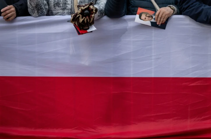 Une femme tient un tract de campagne du maire de Varsovie et candidat à la présidence, Rafal Trzaskowski, alors qu'elle et d'autres partisans de M. Trzaskowski se rassemblent sur le marché principal de Skierniewice, en Pologne, le 16 mai 2025