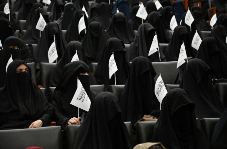 Des étudiantes afghanes en niqabs noirs, un drapeau taliban à la main, écoutent un discours lors d'un rassemblement pro-talibans à l'université Shaheed Rabbani, le 11 septembre 2021 à Kaboul