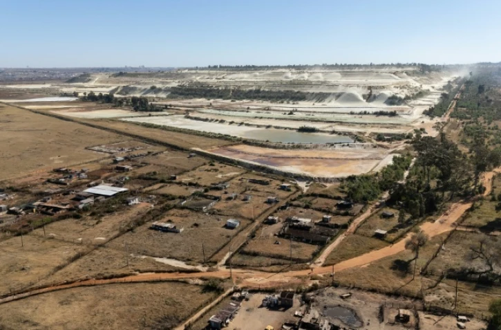 Vue aérienne de parcelles agricoles et de talus miniers en arrière-plan, dans le quartier de Snake Park, à Soweto, le 30 mai 2025 en Afrique du Sud