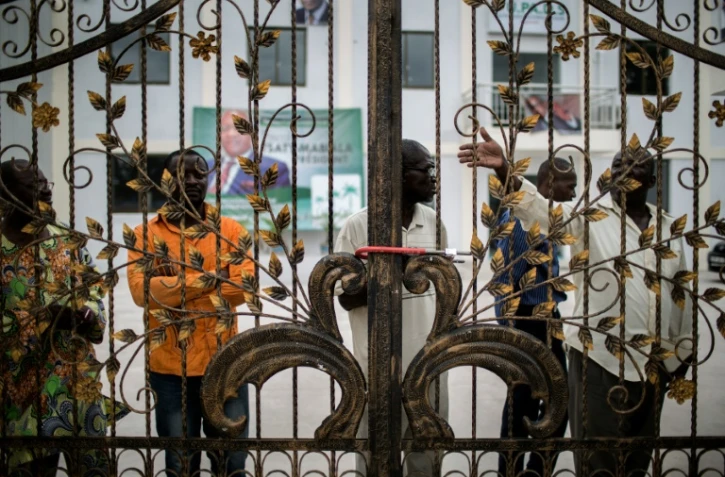 Des militants du parti d'opposition congolais UPADS derrière les grilles cadenassées du siège de leur parti à Brazzaville, le 25 mars 2016