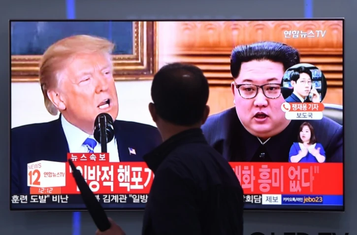 Un homme devant un écran de télévision montrant le président américain Donald Trump et le leader nord-coréen Kim Jong Un, à Séoul le 16 mai 2018