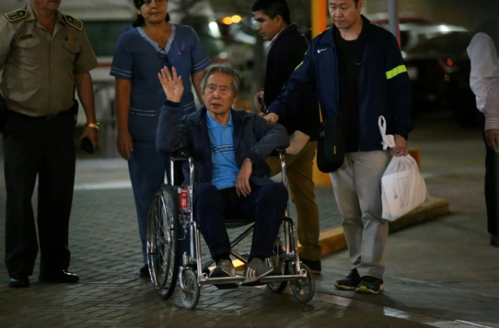 L'ancien président péruvien (1990-2000) Alberto Fujimori salue ses supporteurs alors qu'il est escorté hors de la clinique Centenario par son fils, le député Kenji Fujimori, à Lima, le 04 janvier 2018