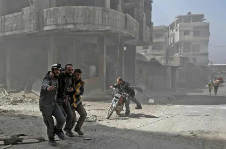 Des secouristes des Casques blancs aident un homme après un bombardement sur la ville de Hammouriyé, dans la Ghouta orientale, le 6 mars 2018