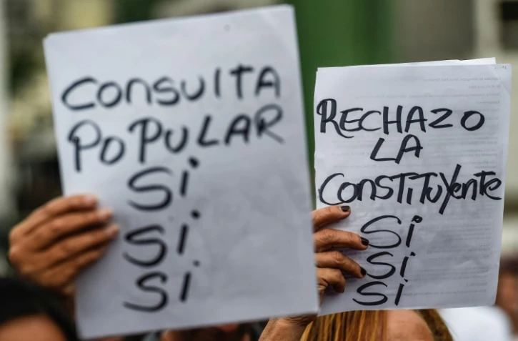 Des manifestants portent des pancartes contre la Constituante du président vénézuélien Nicolas Maduro et en faveur d'une consultation populaire symbolique organisée par l'opposition, le 15 juillet 2017 à Caracas