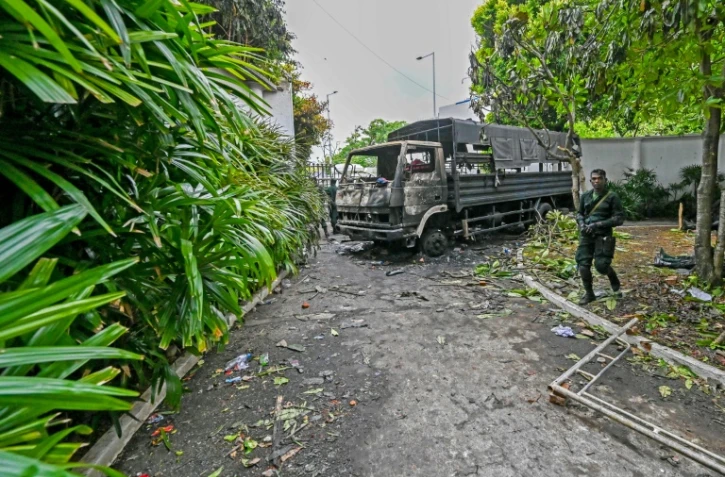 Des soldats sri-lankais montent la garde le 10 mai 2022 près d'un camion incendié par des manifestants devant la résidence du Premier ministre démissionnaire Mahinda Rajapaksa