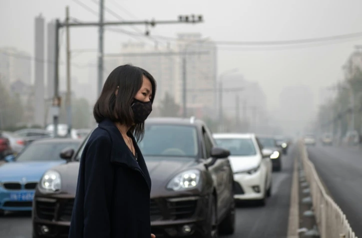 Une femme se protège de la pollution avec un masque à Pékin, en novembre 2018