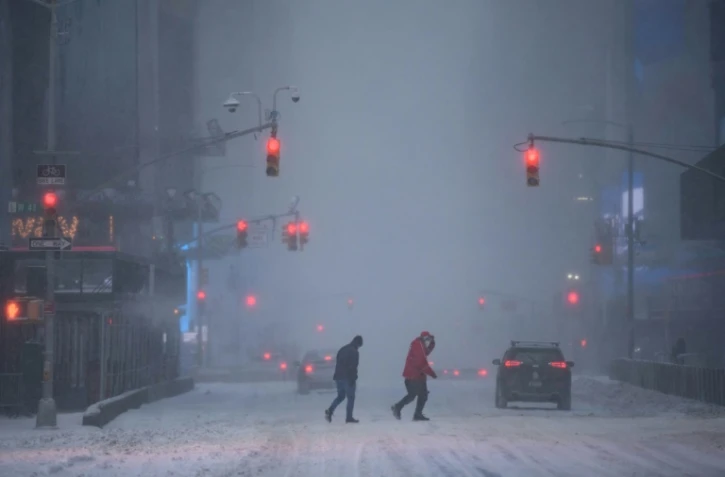 Des passants dans un Times Square sous la neige, à New York, le 29 janvier 2022