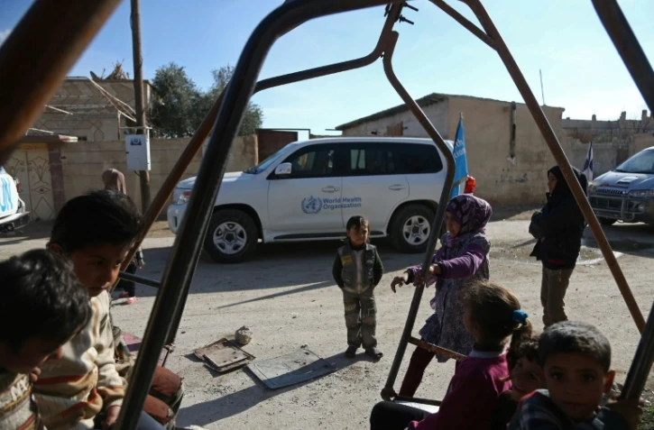 Des enfants dans les rues de la ville d'Utaya, dans l'enclave syrienne de la Ghouta Orientale, tandis qu'un convoi d'aide humanitaire pénètre dans la ville le 14 février 2018