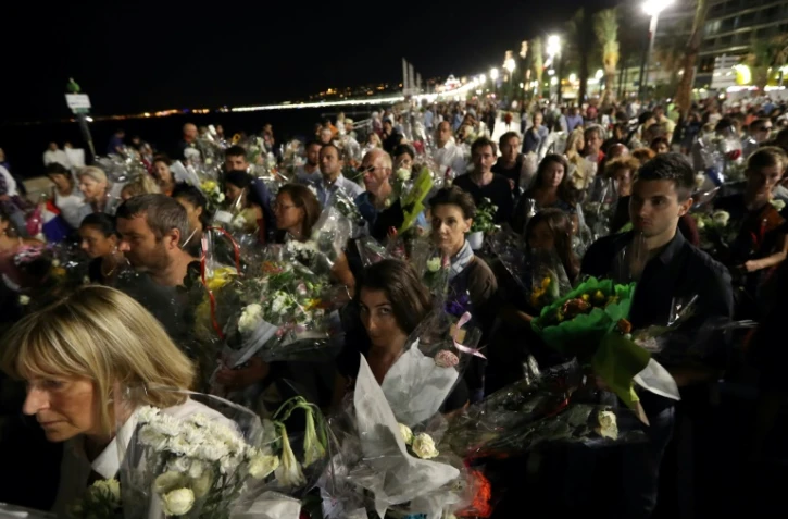 Une chaîne humaine déplace les bouquets déposés sur la Promenade des Anglais en hommage aux victimes de l'attentat du 14 juillet vers le front de mer à Nice le 18 juillet 2016