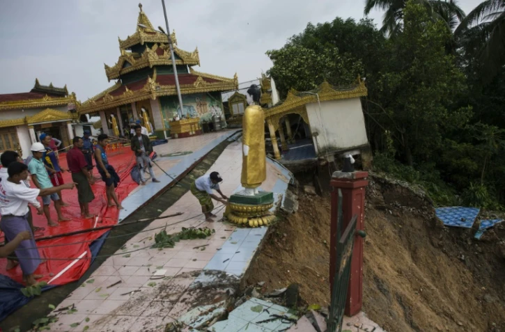 Des ouvriers déplacent une statue de Bouddha de la pagode Kyeik Than Lan, dans le sud de la Birmanie, endommagée par un glissement de terrain, le 18 juin 2018