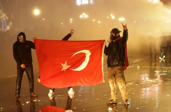 Des manifestants tiennent le drapeau turc lors de heurts avec la police, le 23mars 2025 à Ankara