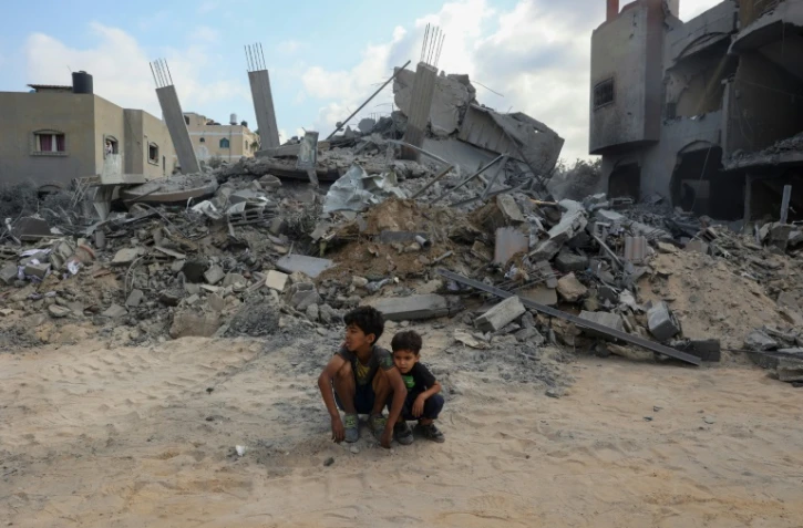 Des enfants sont assis devant une montagne de gravats après un bombardement à Nousseirat, dans le centre de la bande de Gaza, le 12 août 2024
