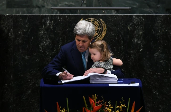 Le secrétaire d'Etat américain John Kerry signe l'accord sur le climat tenant sa petite-fille, à l'ONU à New York, le 22 avril 2016 