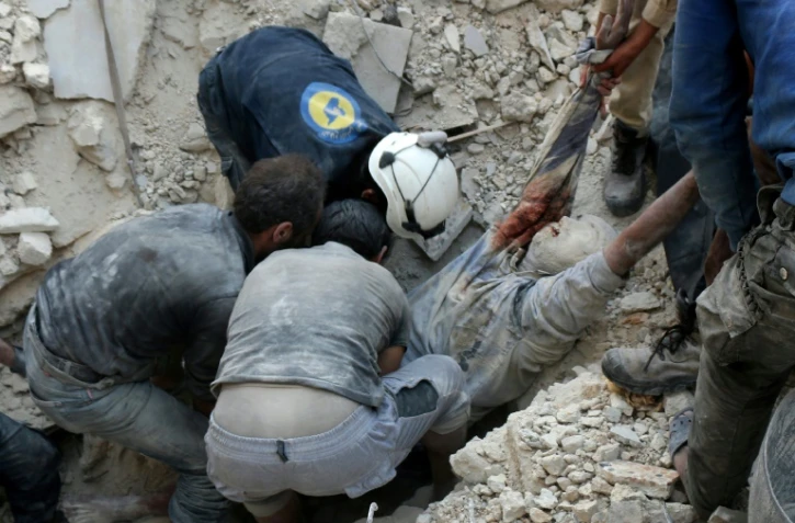 Des Syriens sauveteurs volontaires dénommés Casques blancs récupèrent des blessés et des morts après des bombardements aériens sur un quartier nord de Alep, le 4 octobre 2016