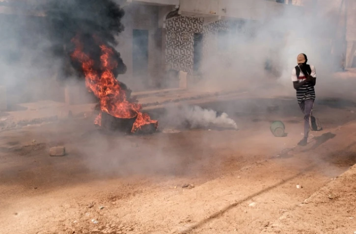 Un manifestant se protège le visage contre les gaz lacrymogènes lors de heurts avec la police, le 9 février 2024 à Dakar, au Sénégal