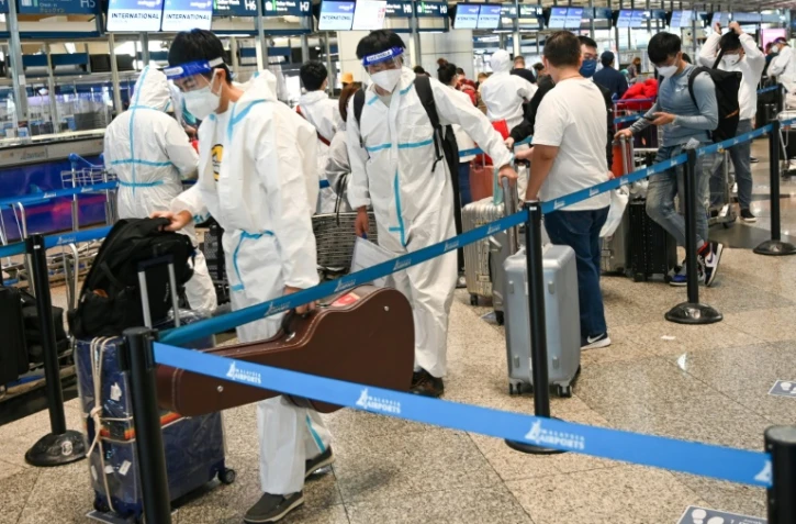 Des passagers vêtus de tenue de protection font la queue à l'enregistrement à l'aéroport de Kuala Lumpur, à Sepang, le 29 novembre 2021