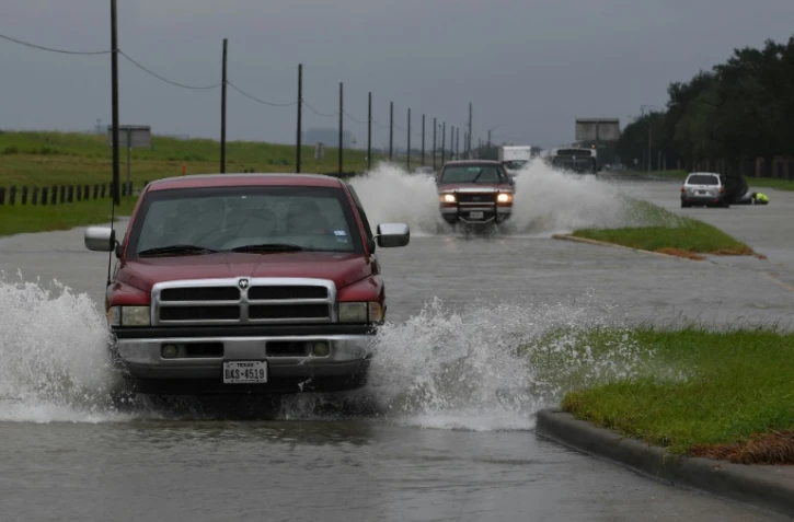 Des véhicules roulent sur une route inondée dans l'agglomération de Houston, le 29 août 2017