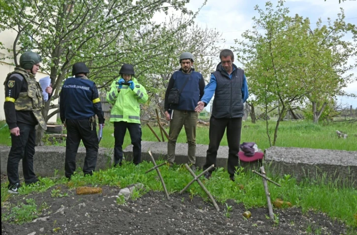 Un Ukrainien désigne à des enquêteurs la fosse où trois civils ont été enterrés dans le village de Stepanky, près de Kharkiv, le 11 mai 2022